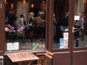 The queue of people lining up to get into Frenchie’s bar, seen in a reflection on a window of Frenchie’s restaurant, just across the alley